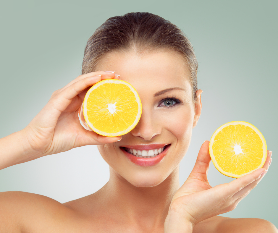 Vitamin C Beauty Drops | 8thereal | Woman holding half cut orange over one eye and smiling holding another orange half above her shoulder. They appear bright orange and radiant, reflecting the benefits and joy of 8thereal Vitamin C Beauty Products. 