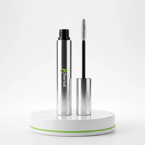 8thereal clear eyebrow gel in a sleek silver tube with a spoolie applicator on a white pedestal