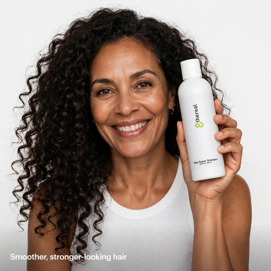 Woman with curly hair holding 8thereal Daily Strengthening Repair Shampoo in a white bottle against a white background.