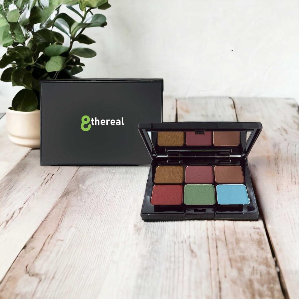 8thereal 6-shade eyeshadow palette with matte and shimmer finishes in a black compact on a rustic wooden table.