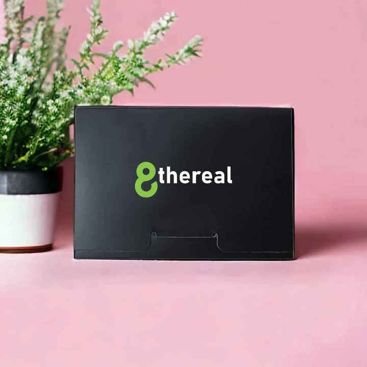 8thereal facial blotting papers in a sleek black compact box on a pink background with a plant in the background