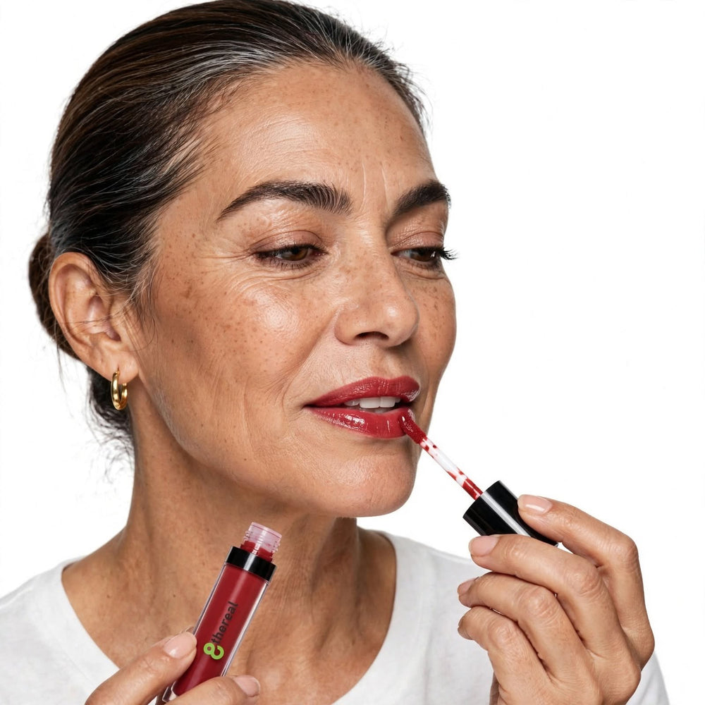 8thereal High-Shine Lip Gloss in a deep red shade being applied to lips by a woman with a radiant, polished look.