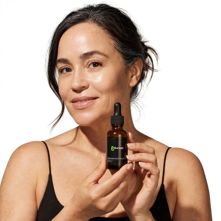 8thereal Luminous Hyaluronic Acid Serum held by a smiling woman with radiant skin, showcasing the 30ml amber glass bottle.