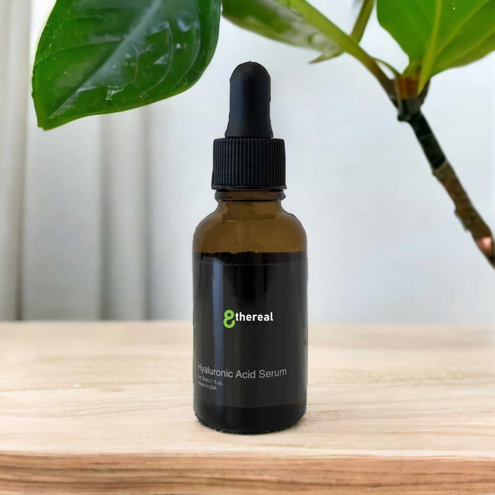 8thereal Luminous Hyaluronic Acid Serum in a brown glass dropper bottle on a wooden surface with green leaves behind.