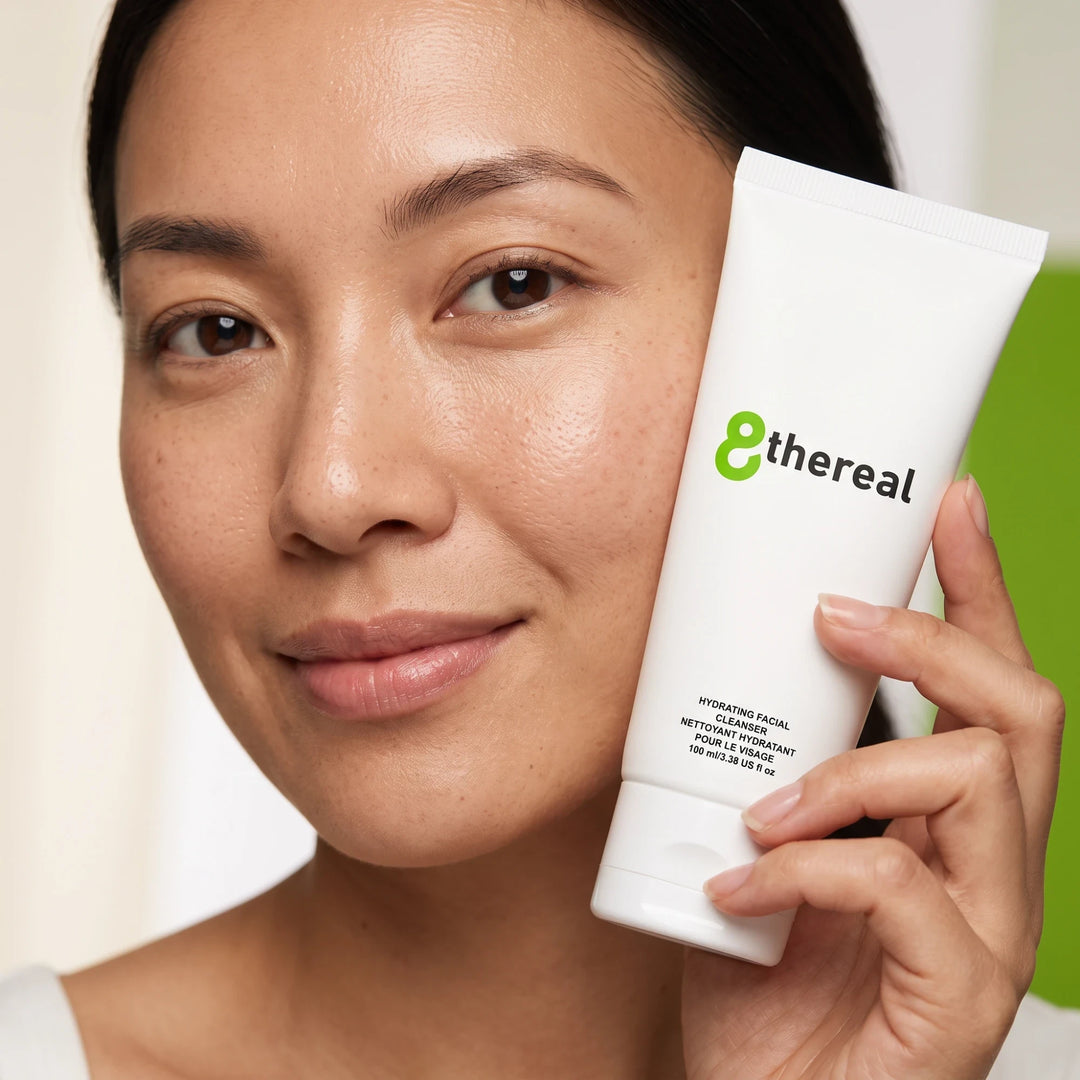 8thereal Hydrating Facial Cleanser held by a woman with glowing skin, showcasing the white squeeze tube packaging.