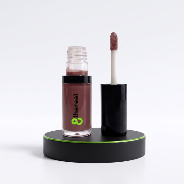 8thereal hydrating lip oil in a mauve shade with a doe-foot applicator, displayed on a black circular pedestal.