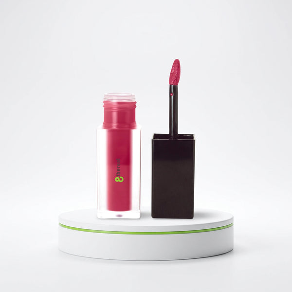 8thereal matte lip stain in a frosted glass bottle with a black applicator wand on a white display pedestal