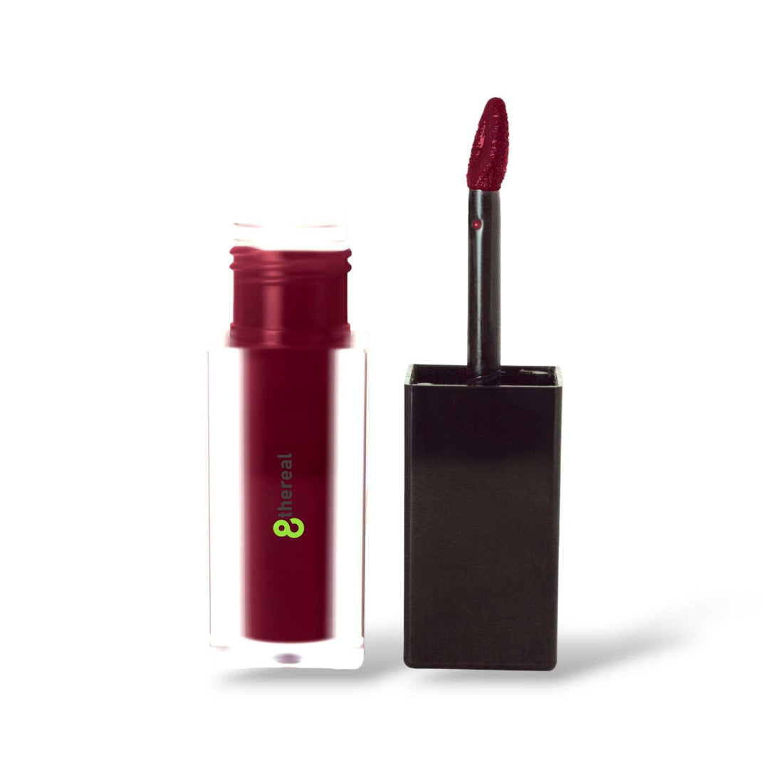 8thereal matte lip stain in a deep berry shade with a doe-foot applicator, shown in a clear square bottle.