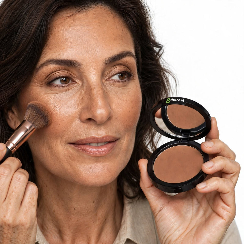 8thereal Natural Warmth Bronzer applied to a woman's cheek with a brush, showing a smooth, radiant, sun-kissed finish.