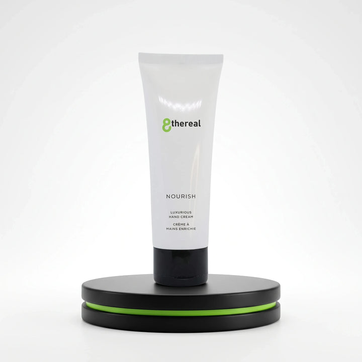 8thereal Restorative Nourish Hand Cream in a white squeeze tube with black cap, displayed on a black and green pedestal.