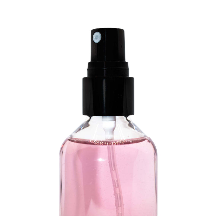 8thereal oil control setting spray in a clear bottle with pink liquid and a black spray nozzle.