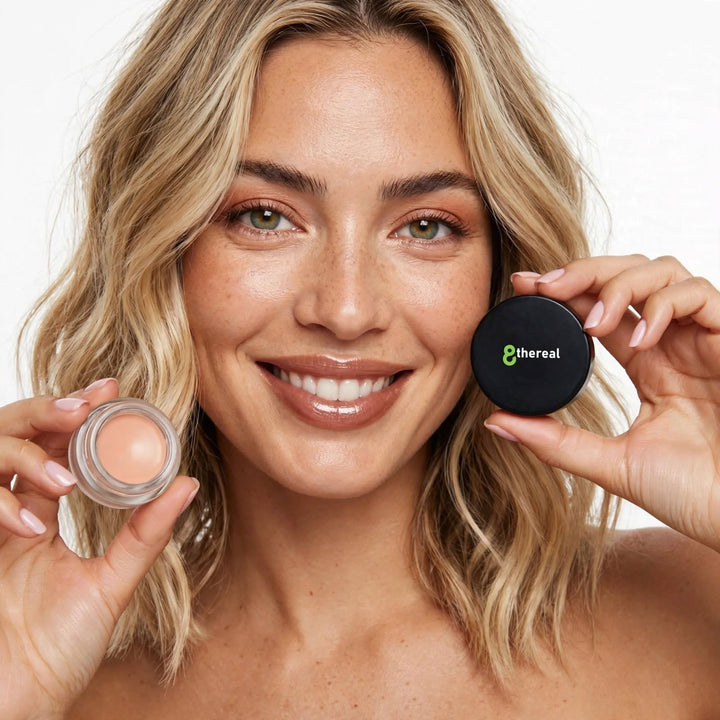8thereal smoothing eye and lip primer in a small jar held by a smiling woman with natural makeup