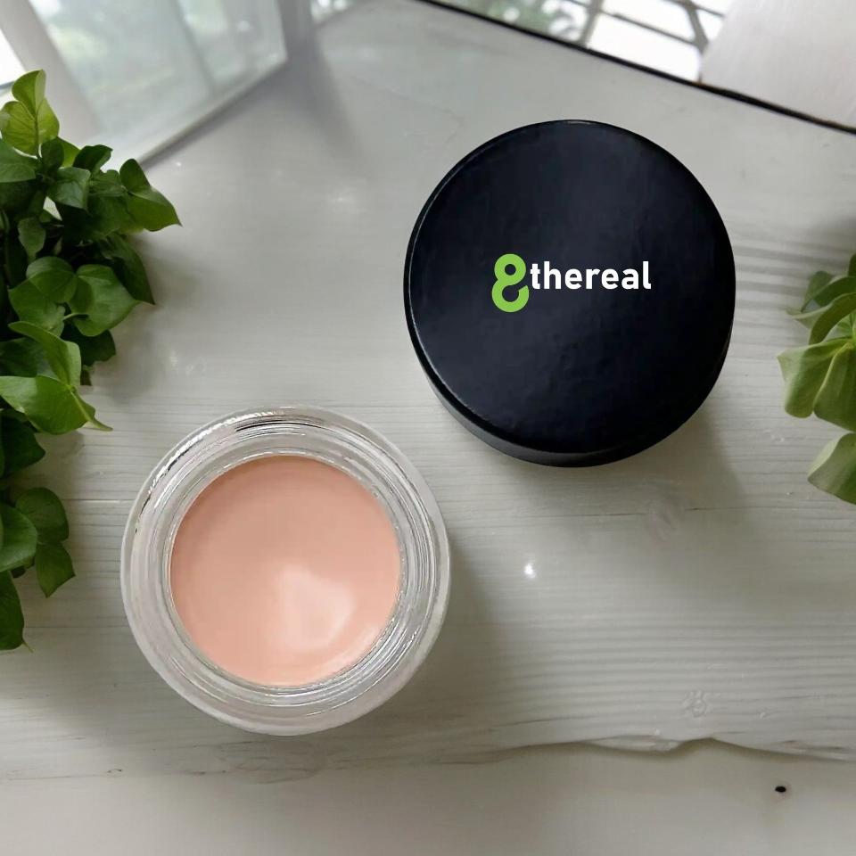8thereal smoothing eye and lip primer in a small glass jar with a black lid, featuring a creamy peach-toned formula.