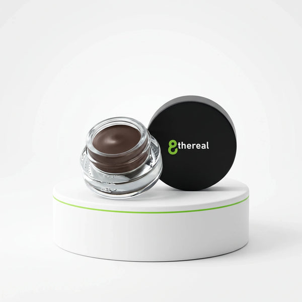 8thereal Soft Sculpt Brow Pomade in a glass jar with a black lid, displayed on a white pedestal.