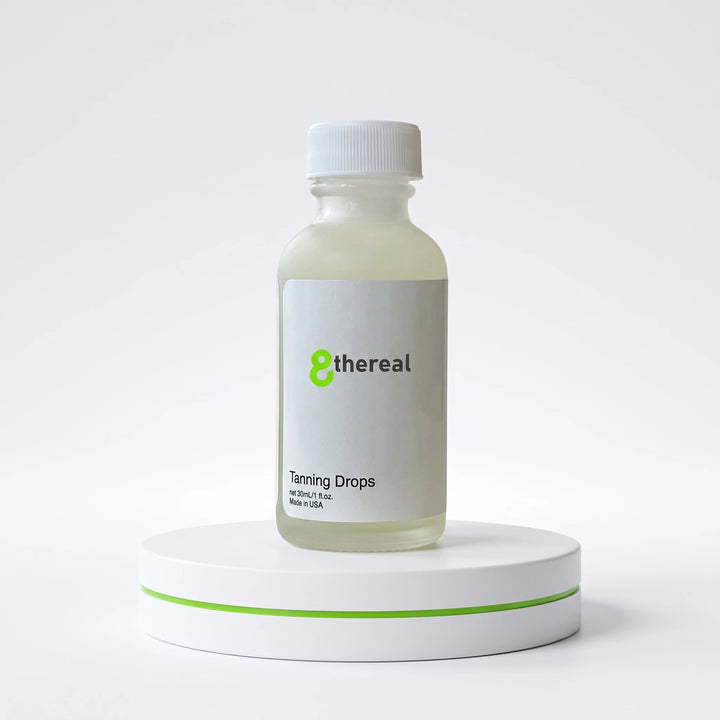 8thereal Sunlit Glow Tanning Drops in a clear glass bottle with a white cap, displayed on a white pedestal.