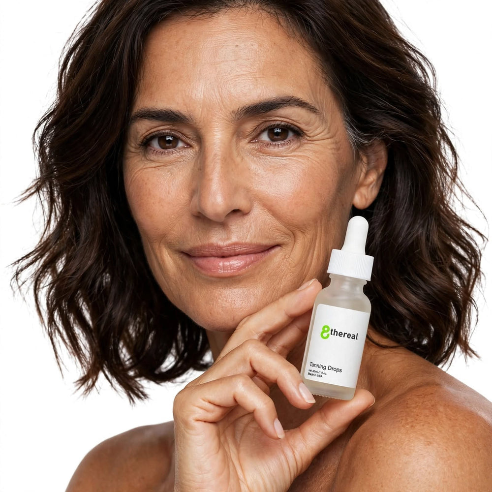 A smiling woman holding a bottle of 8thereal Sunlit Glow Tanning Drops, a lightweight serum for a natural tan.
