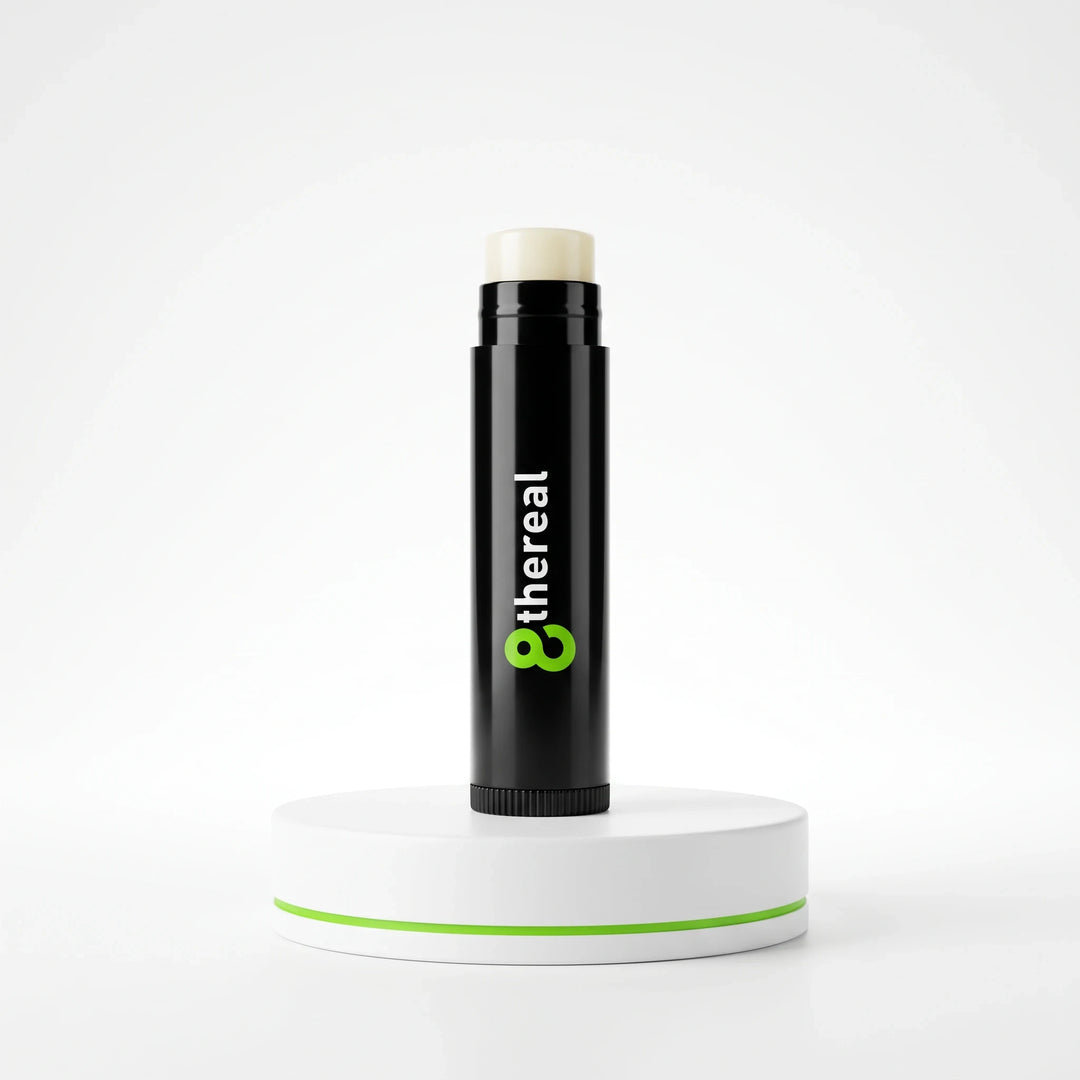 8thereal vegan lip balm in a sleek black twist-up tube, displayed on a white circular pedestal against a white background