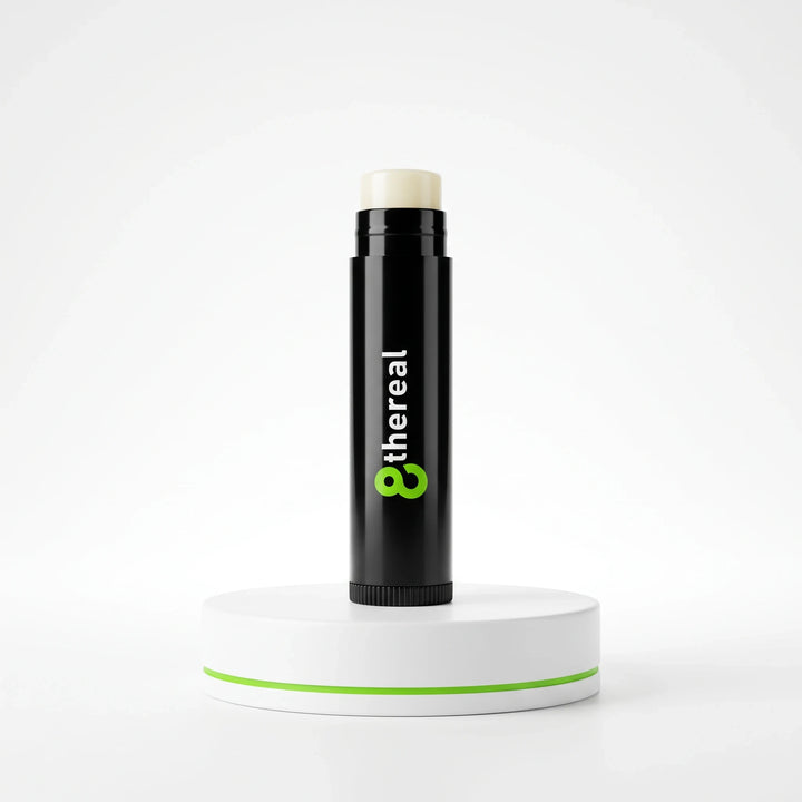 8thereal vegan lip balm in a sleek black twist-up tube, displayed on a white circular pedestal against a white background