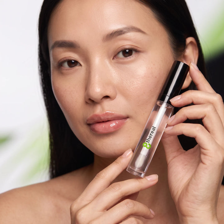 8thereal clear lip plumper gloss held by a model with hydrated, shiny lips for a fuller appearance